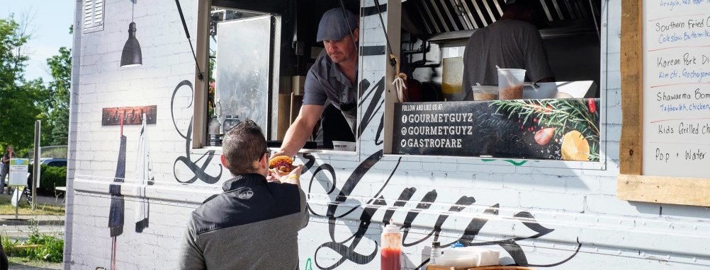 A man serving a customer from a food truck.
