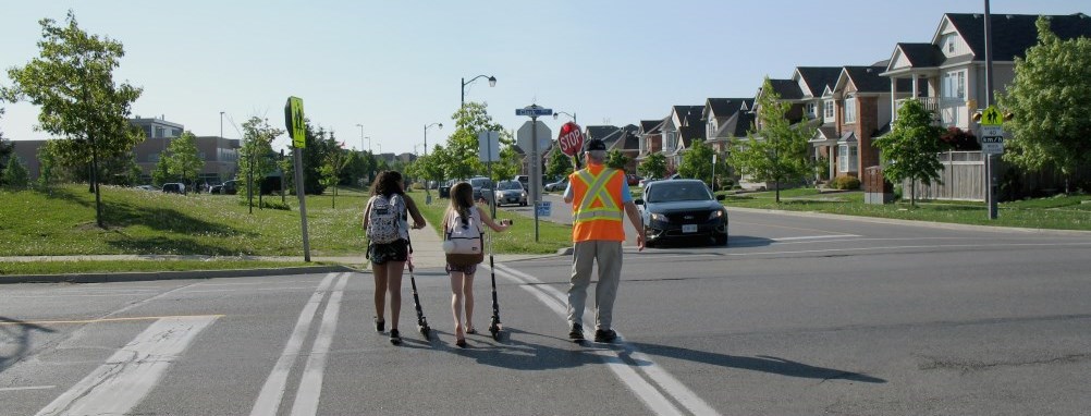 crossing guard walking 2 children across a Milton street